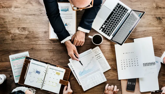 Meja kerja dengan formulir pengembalian pajak, agenda, dan laporan grafik